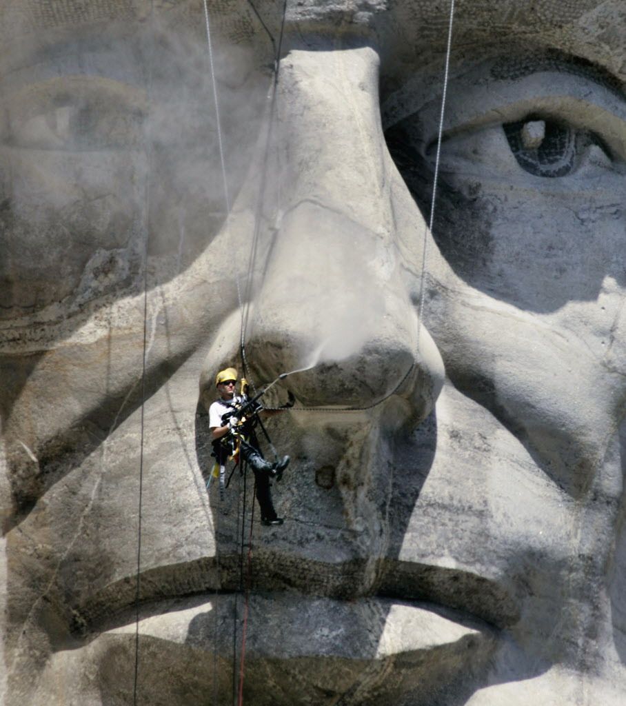 In this July 18, 2005, file photo, Jens Kranhold, of Germany, pressure washes President Abraham Lincoln’s nose at the Mount Rushmore National Memorial in the Black Hills near Keystone, S.D. In October 2016, the memorial will mark 75 years. | AP Photo/Char
