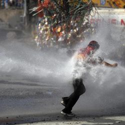 FILE - In this Tuesday, June 11, 2013, file photo, a protester tries to remain standing as a police water cannon fires water during clashes in Taksim square in Istanbul. Hundreds of police in riot gear forced through barricades in Istanbul's central Taksim Square early Tuesday, pushing many of the protesters who had occupied the square for more than a week into a nearby park. 