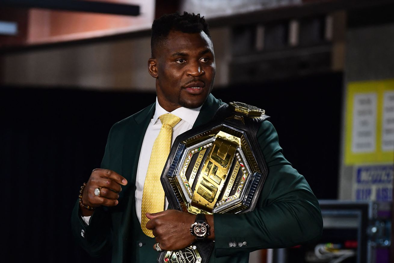 Francis Ngannou, holding his UFC heavyweight title, while speaking to the media.