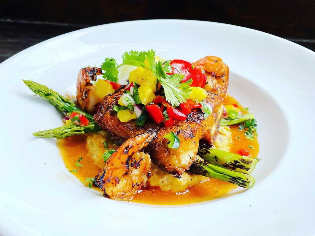 Seared wild striped bass and grilled jumbo shrimp, topped with a pineapple salsa, served with roasted corn grits, grilled asparagus, and a New Mexico red chile sauce.