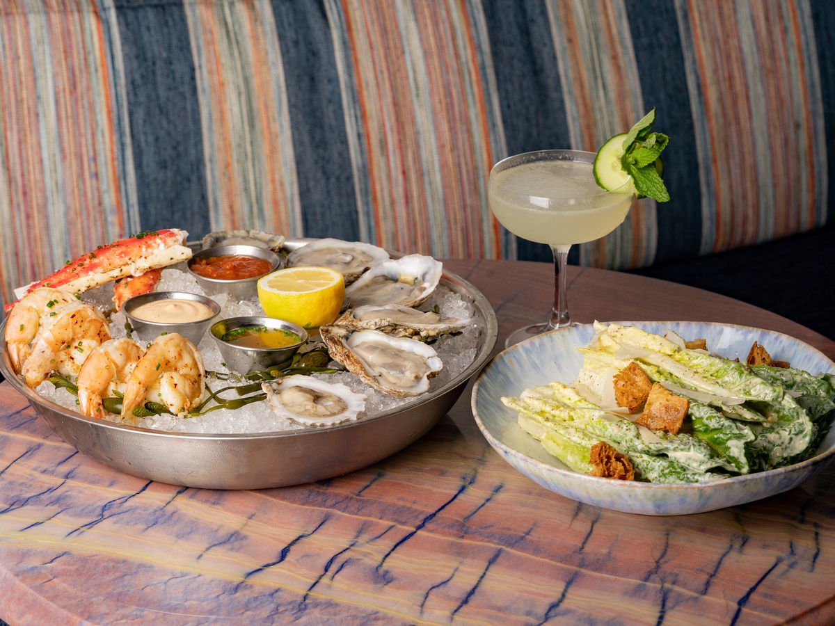 A seafood platter and caesar salad on a wooden table.