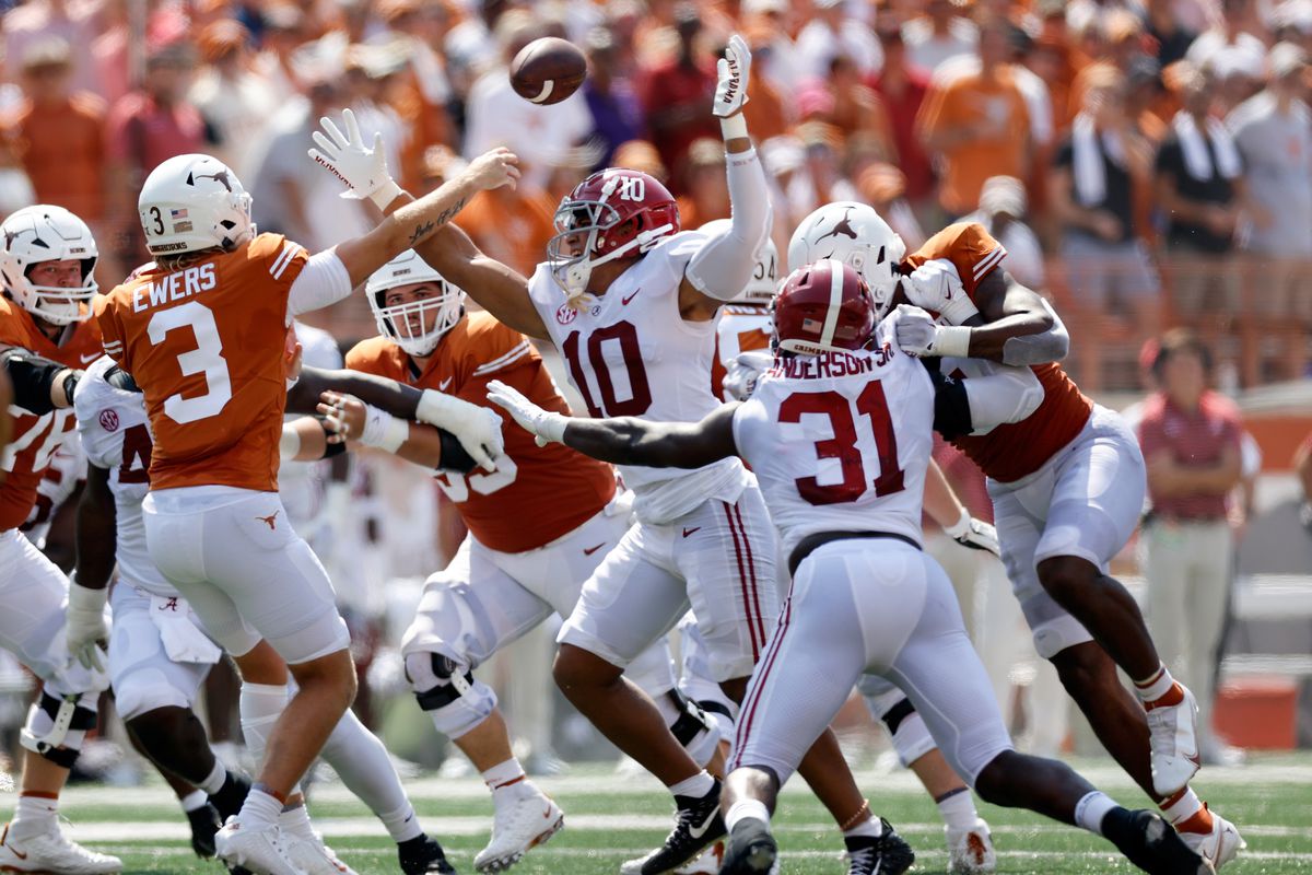 Quinn Ewers of the Texas Longhorns throws a pass under pressure by Henry To’oTo’o of the Alabama Crimson Tide and Will Anderson Jr. in the first half at Darrell K Royal-Texas Memorial Stadium on September 10, 2022 in Austin, Texas.