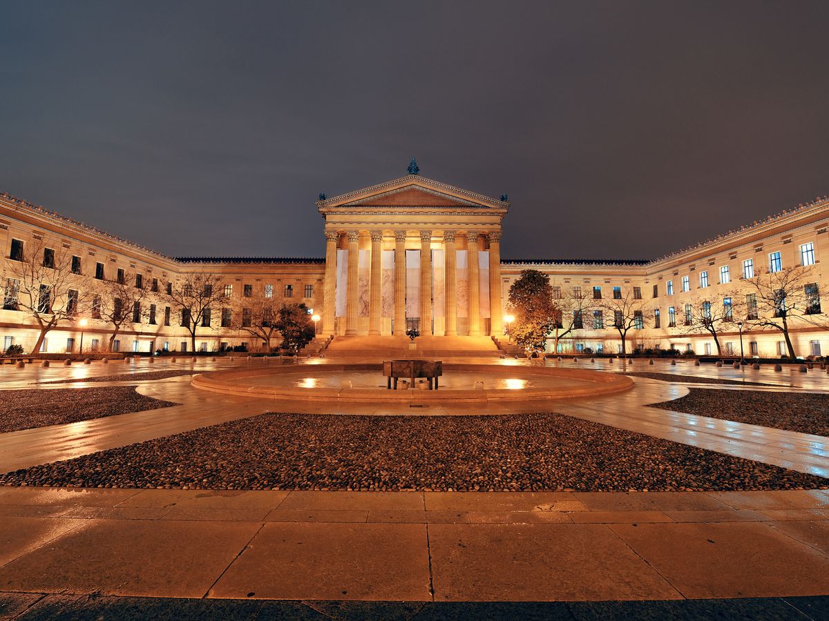 The exterior of the Philadelphia Museum of Art. The museum has columns flanking the entryway and a large courtyard in front.