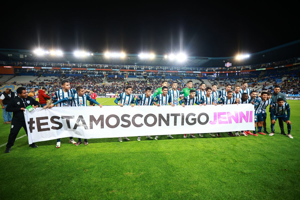 Soccer players on a field holding a banner that reads “Estamos Contigo Jenni.”