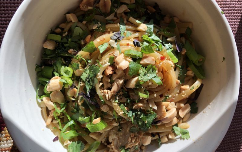 Noodles in a bowl with peanuts and herbs