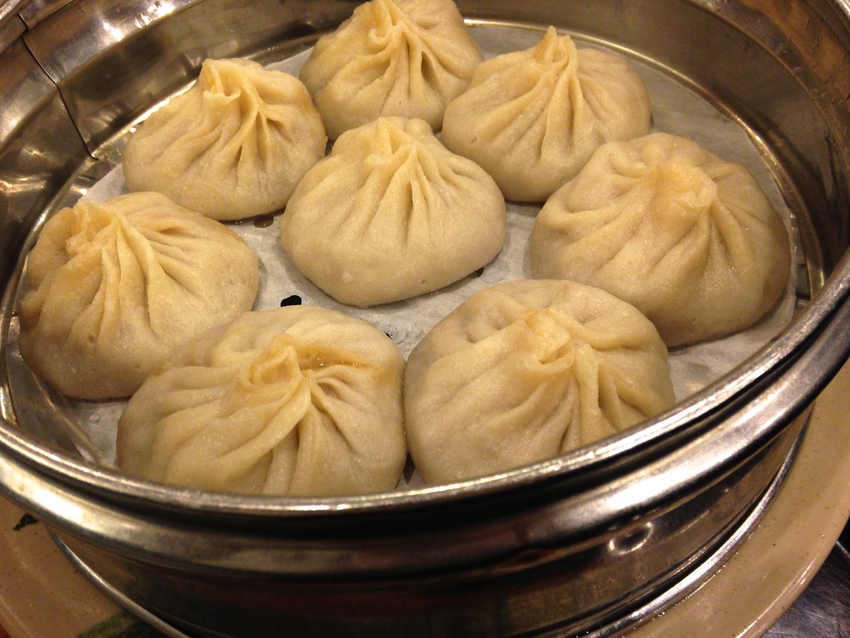 A metal steamer containing eight plump Chinese soup dumplings