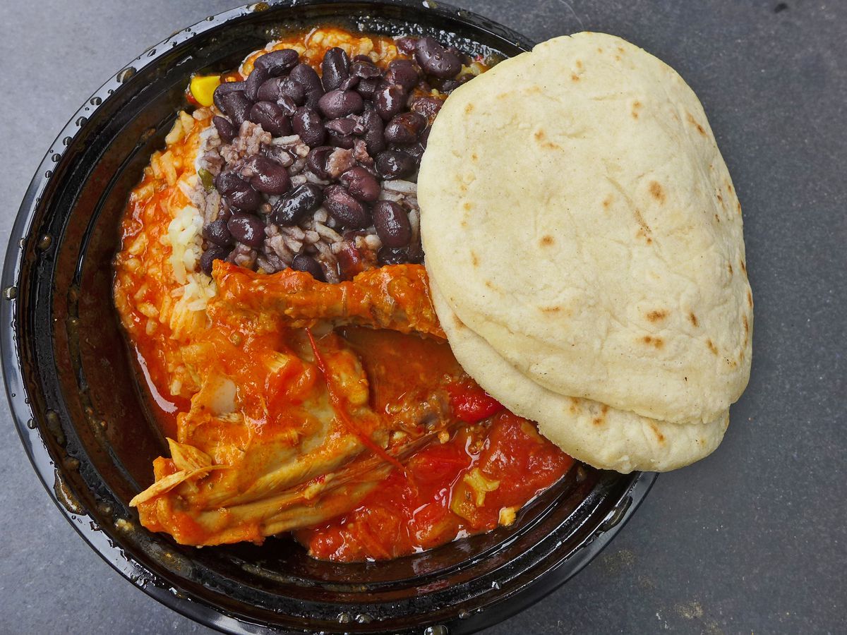 A black plastic tub with red chicken parts and black beans.