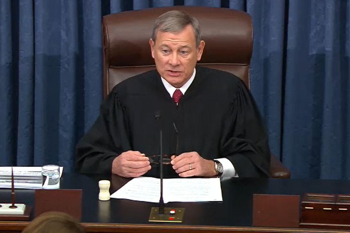 Supreme Court Chief Justice John Roberts sitting at a desk wearing his judicial robe.