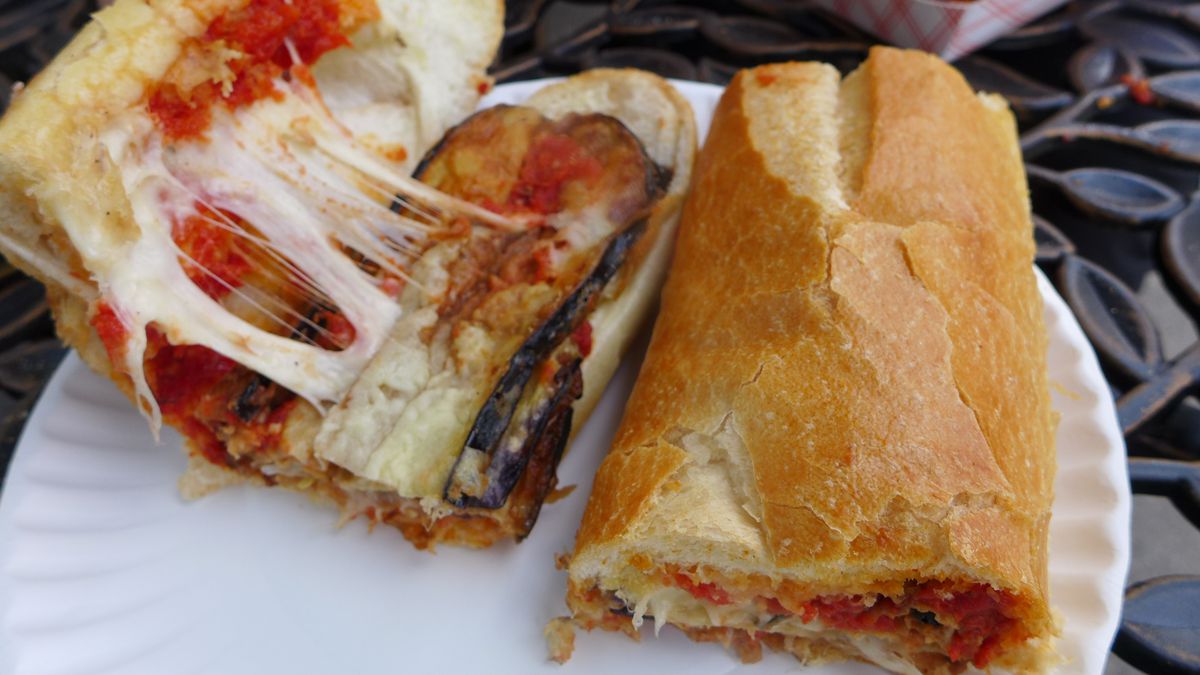 One half of a sub held open to reveal eggplant slices, tomato sauce, and cheese.