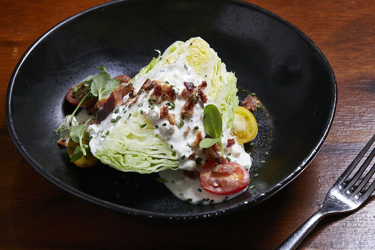 A wedge salad in a black bowl