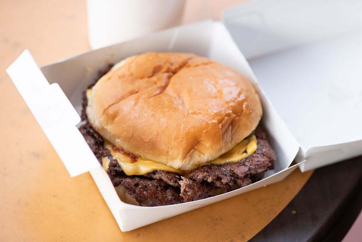 Smash burger with cheese in a to-go box.