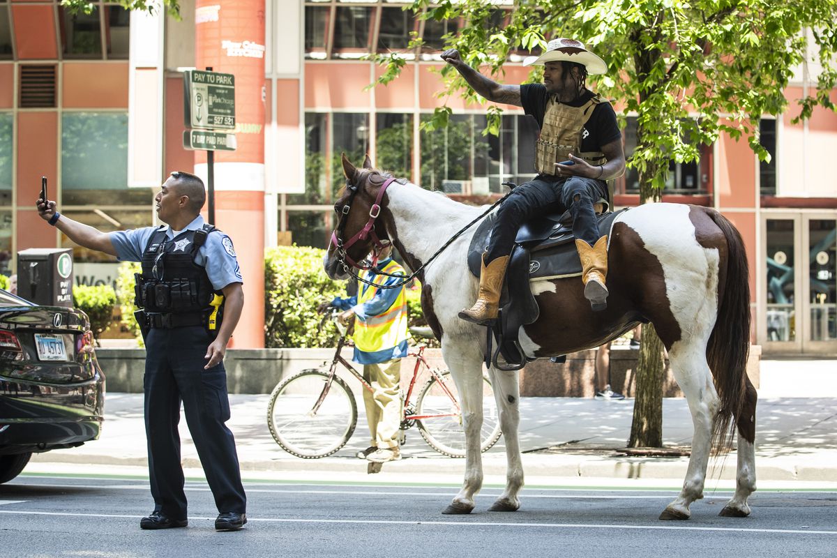 Adam Hollingsworth, 33, otherwise known as “The Dread Head Cowboy,” poses in a selfie with a Chicago Police officer as he rides his horse Prince in the Loop, Tuesday afternoon, June 16, 2020.