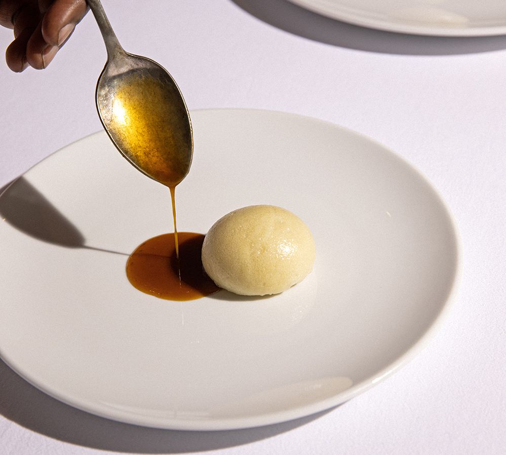 A chef pour sauce beside a ball of uJeqe noMsobho.