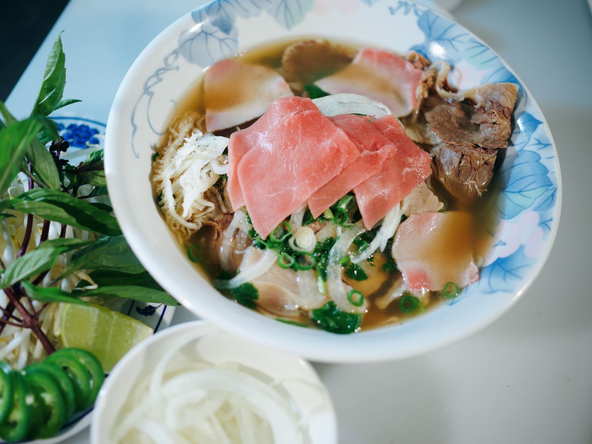 A blue-and-white bowl of pho topped with slices of meat.