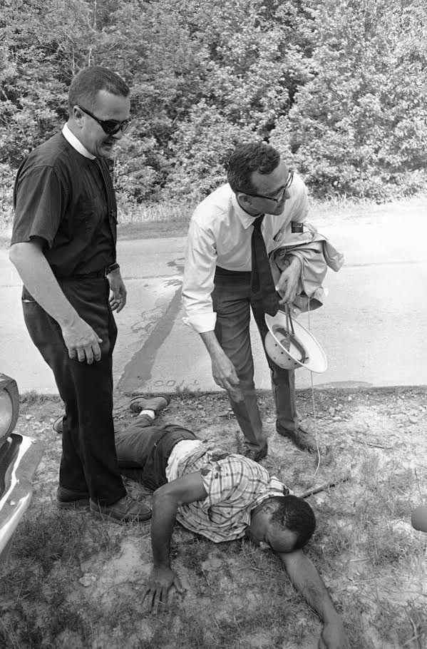 Sherwood Ross (right) bends to help civil rights leader James Meredith, who integrated the University of Mississippi in 1962, after Meredith was shot in Mississippi during the 1966 March Against Fear. | AP