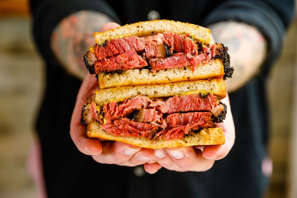 A pastrami sandwich held by two hands