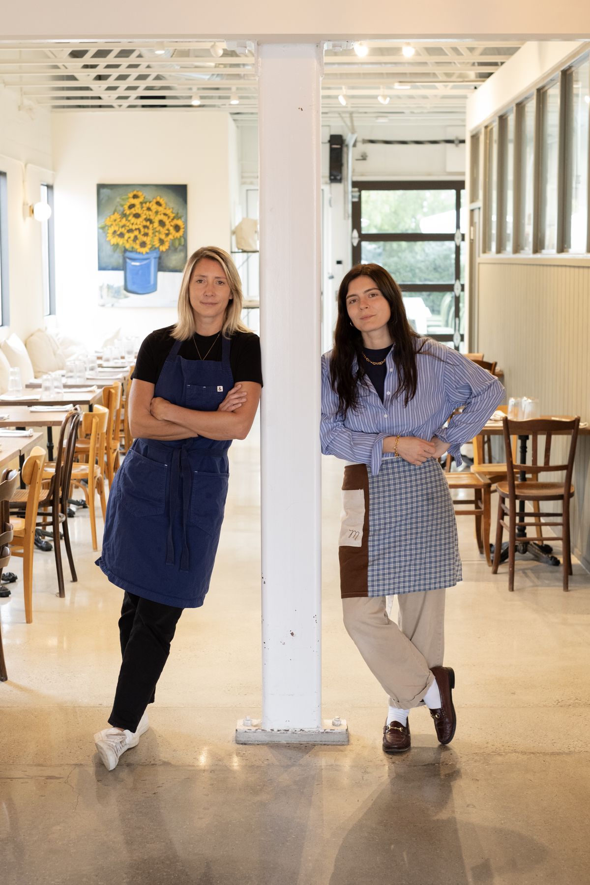 Two women are standing in aprons in their French cafe in Mangette.
