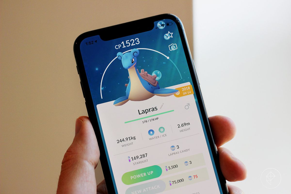 A hand holds up a phone screen with a Lapras stat screen from Pokémon Go