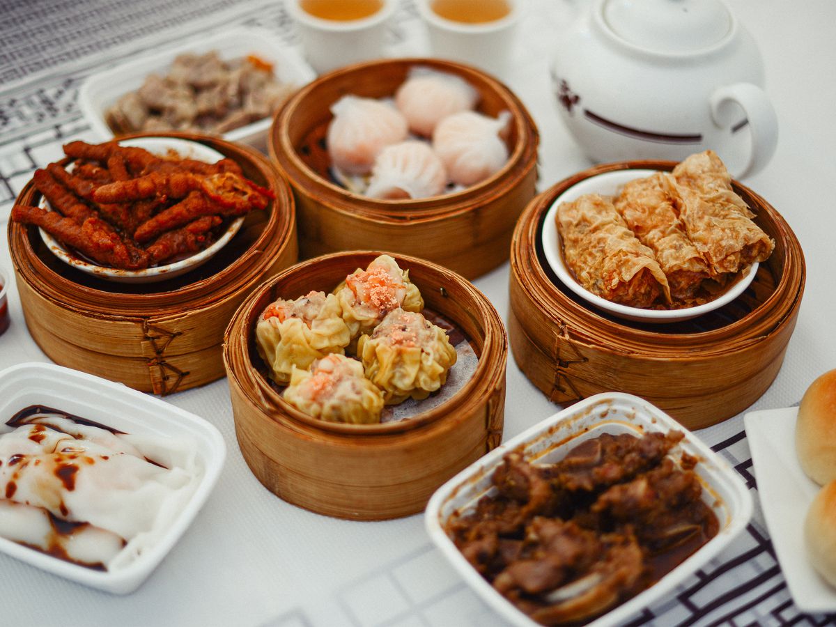 Wooden bowls filled with various dim sum items cover a white table. 