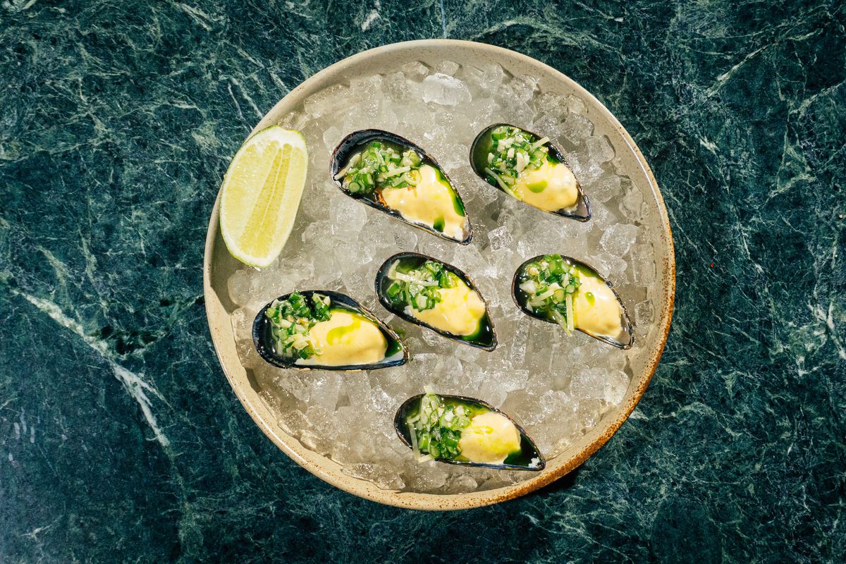 Mussels on ice are dolloped with aioli, and garnished with a slice of lime.