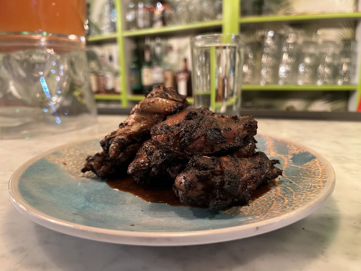 A small pile of jerk wings sit on a patterned blue plate.
