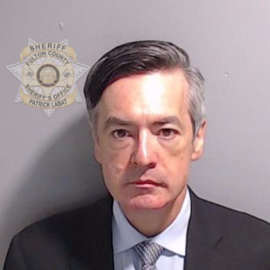 Clean shaven, with gelled salt and pepper hair, Chesebro frowns slightly in his mugshot.