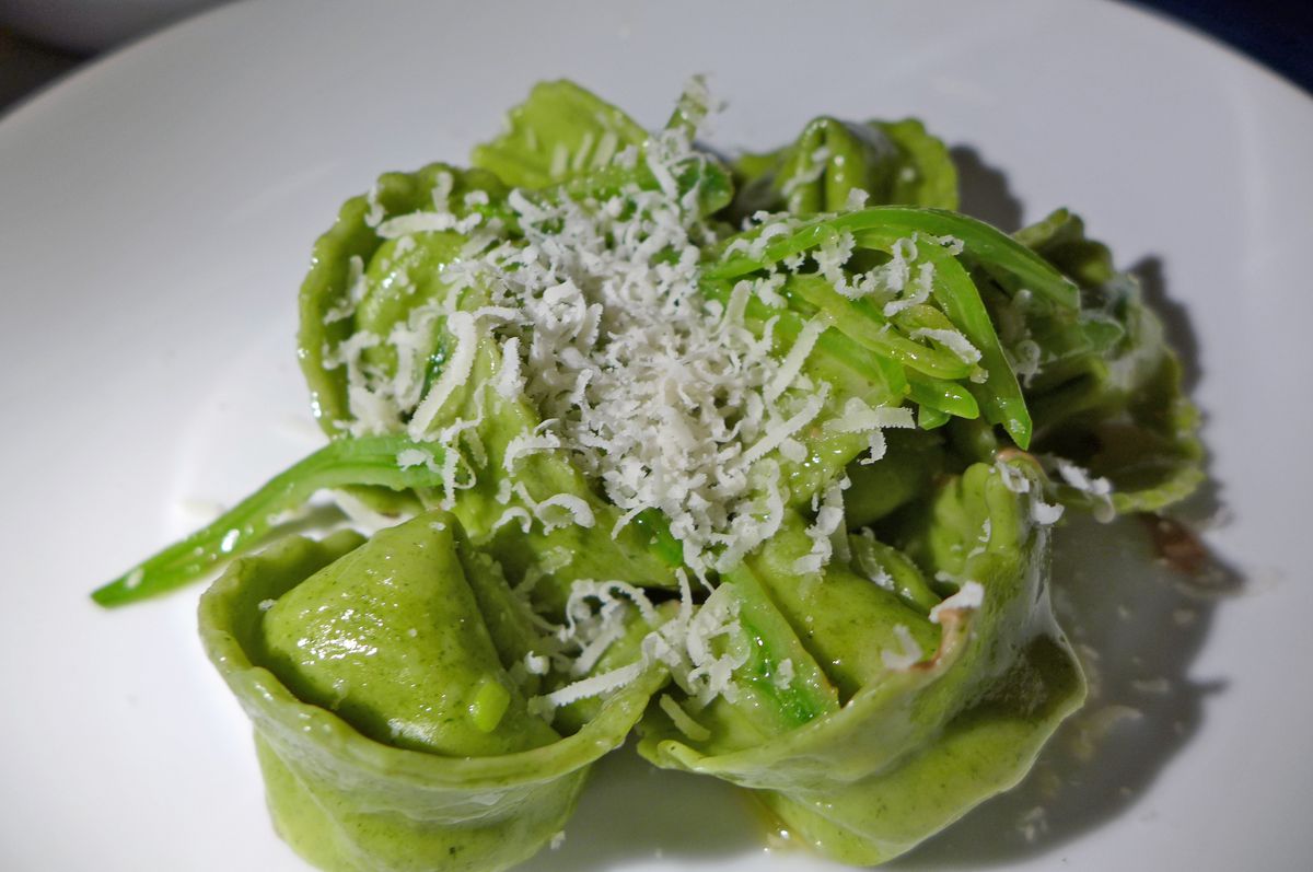 Stuffed green pasta shape like little hats with grated cheese on top.