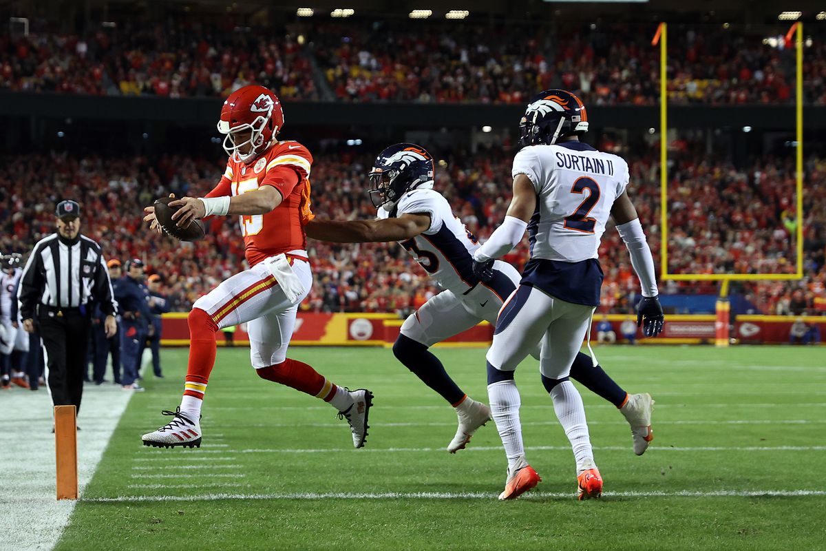 Patrick Mahomes #15 of the Kansas City Chiefs crosses the goal line for a touchdown as Kyle Fuller #23 and Pat Surtain II #2 of the Denver Broncos defend during the first quarter at Arrowhead Stadium on December 05, 2021 in Kansas City, Missouri.