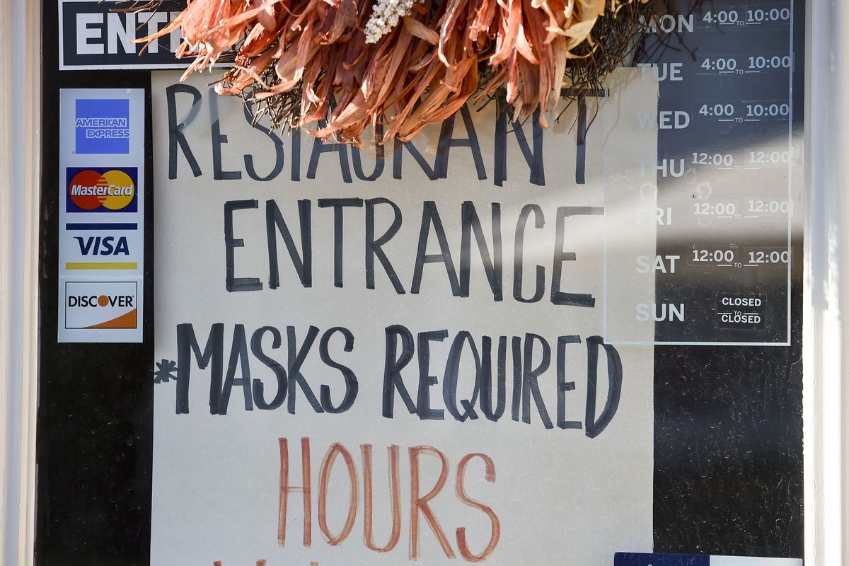 a sign on a door that says restaurant entrance masks required and hours