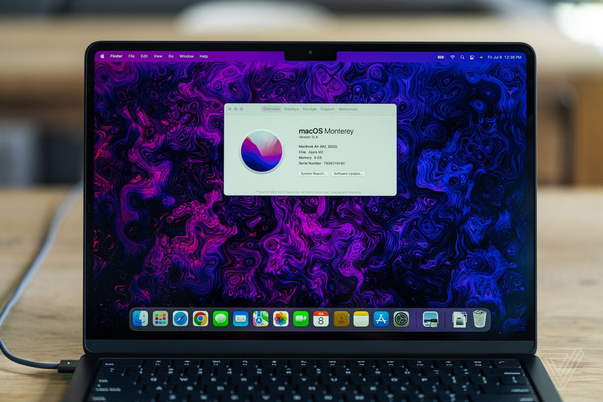 The M2 MacBook Air on a table displaying the About This Mac window over a purple marbled background.