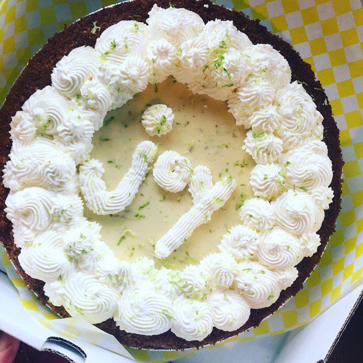 A key lime pie decorated with whipped cream spelling out “joy.”