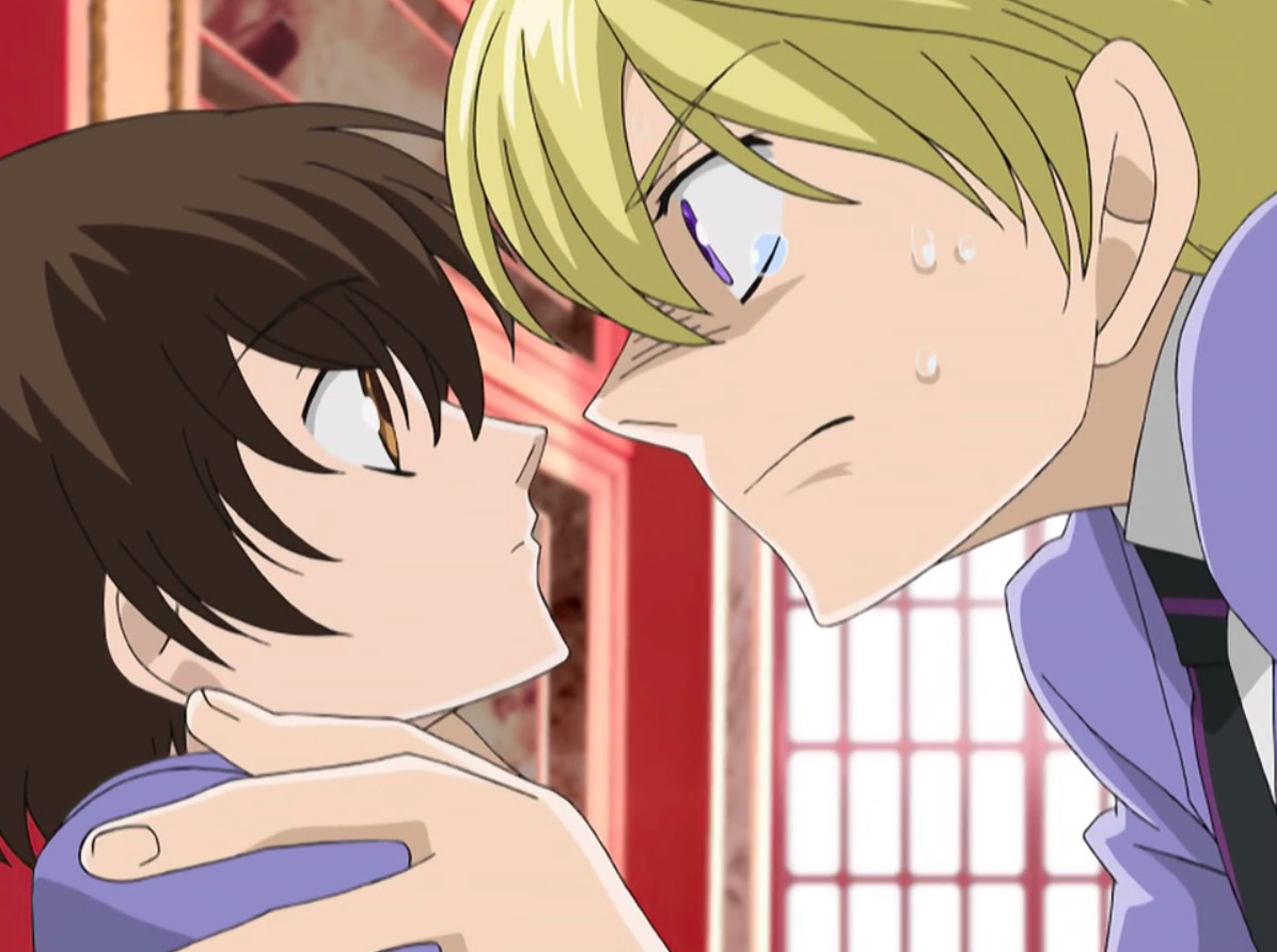 Characters from Ouran High School Host Club — Tamaki, on the right, grips Haruhi by the shoulders. She looks unfazed but is looking back up at him. His expression is intense.