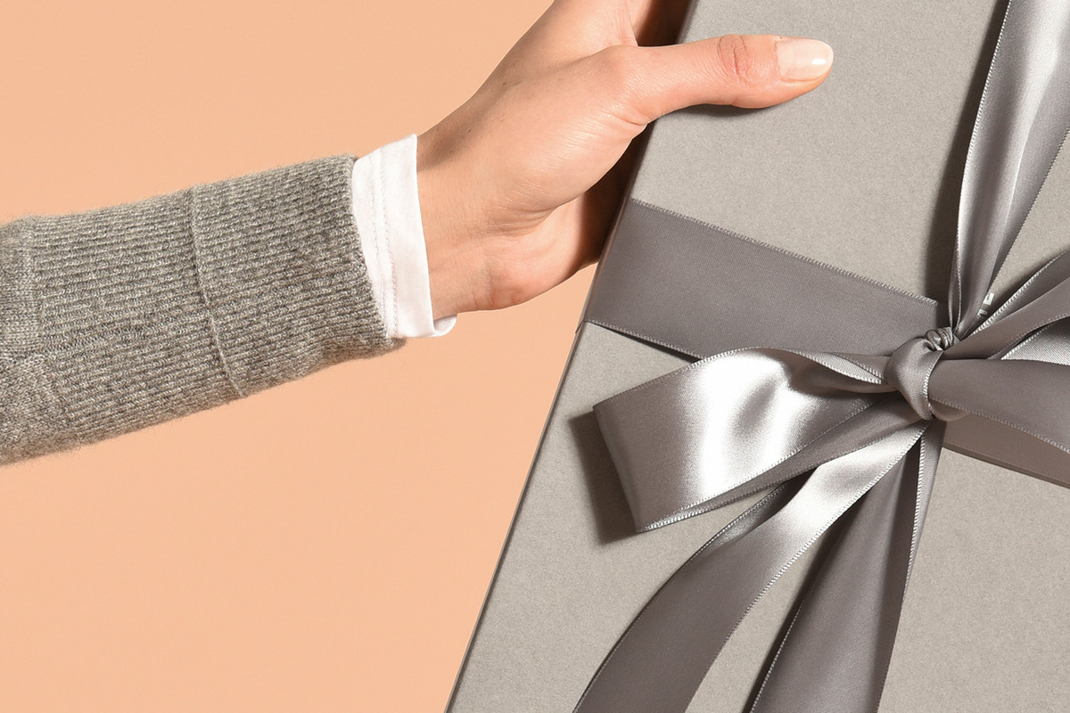A man gives a wrapped gift with a silver bow