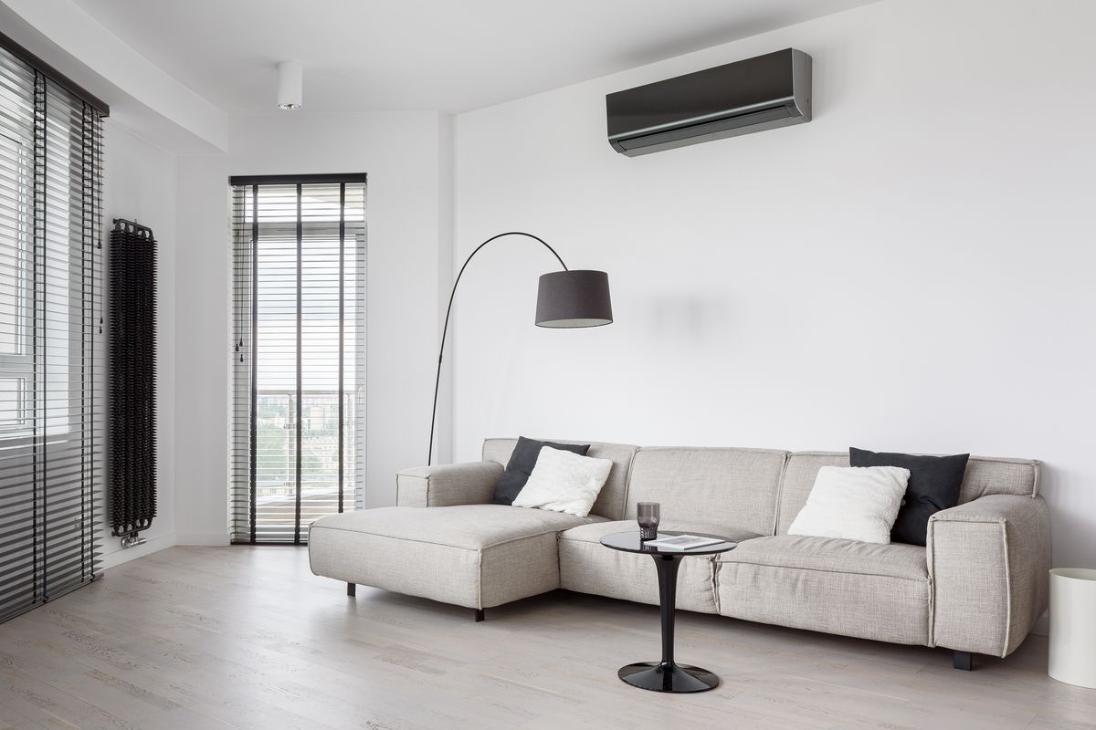 A living room with a black AC mini split unit mounted above the couch