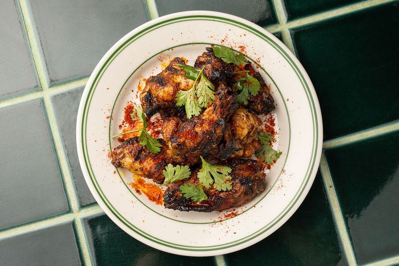 Charred chicken wings dusted with spices and garnished with cilantro.