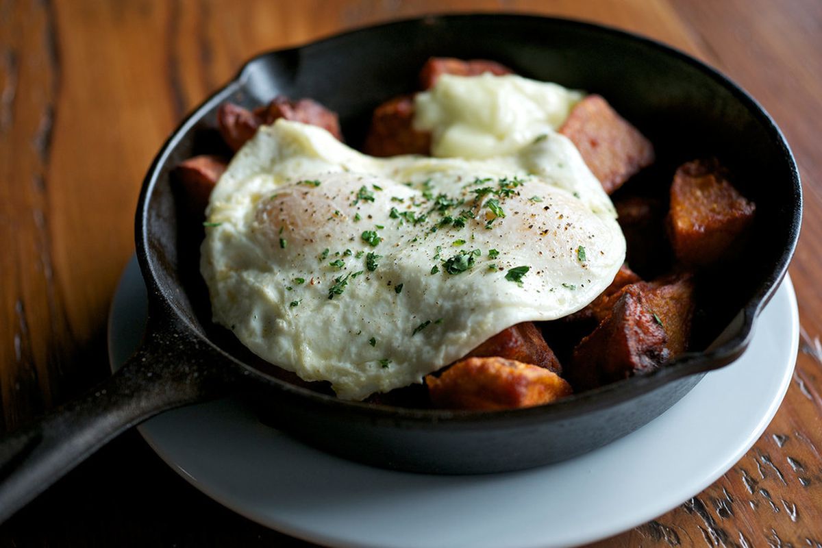 Tasty N Sons potatoes come in a small cast-iron pan with a fried egg draped over top.