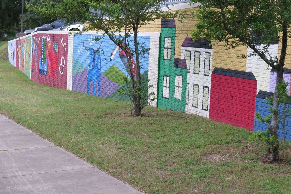 Parking lot retaining wall with painted panels depicting city and other scenes