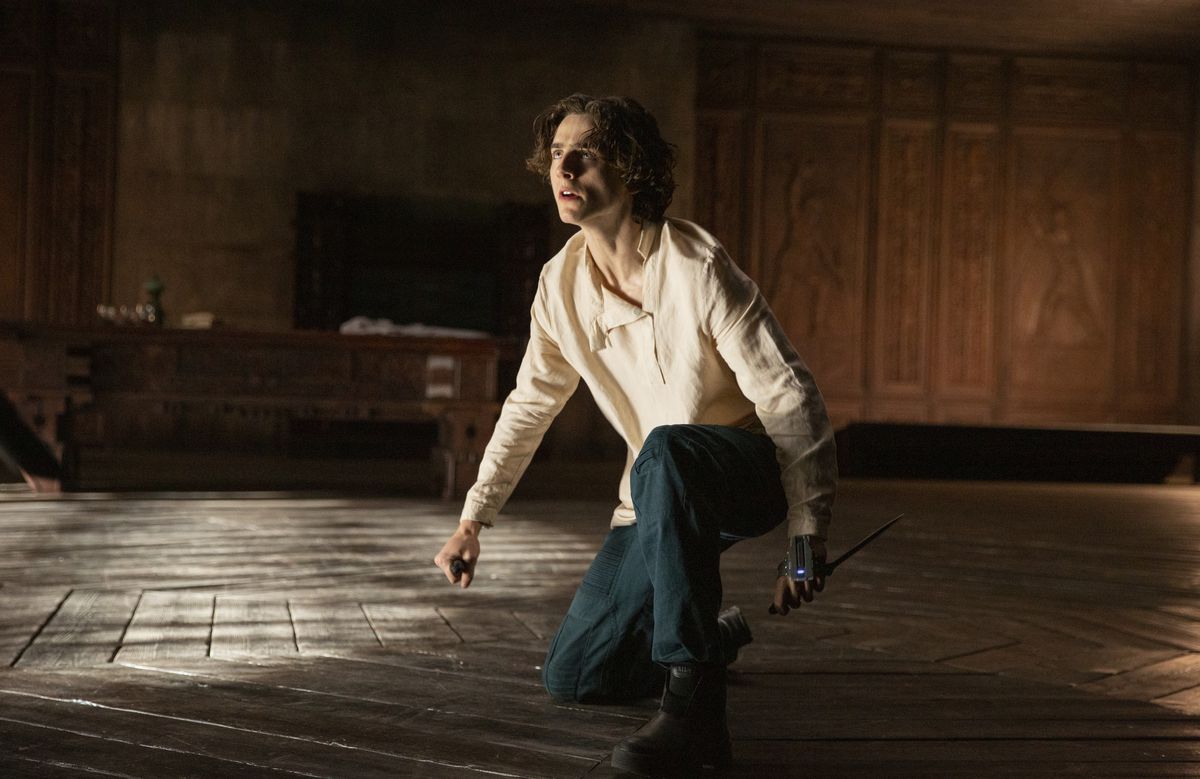 Timothée Chalamet’s Dune character Paul Atreides holds two blades in a battle stance on one knee
