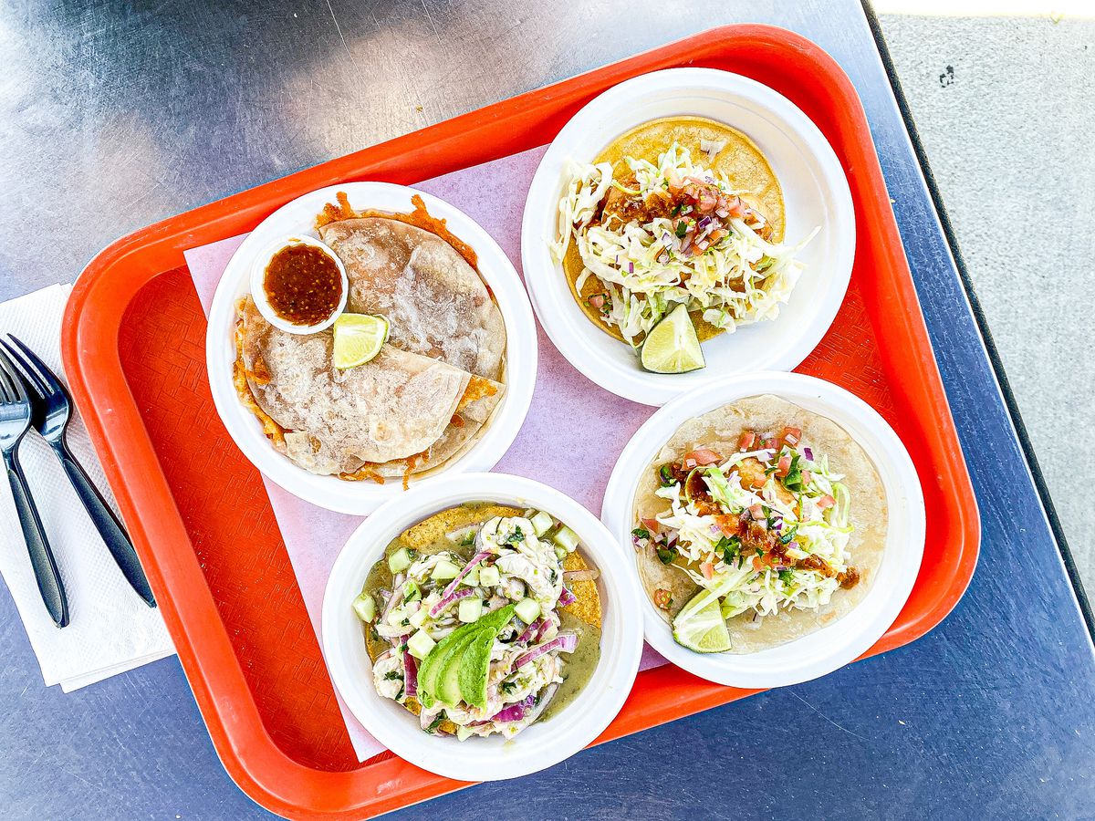 An overhead look at an orange tray filled with different types of seafood, including tacos.