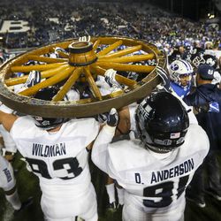 The Utah State Aggies carry the Old Wagon Wheel to midfield after defeating the Cougars and retaining the wheel at LaVell Edwards Stadium in Provo on Friday, Oct. 5, 2018.