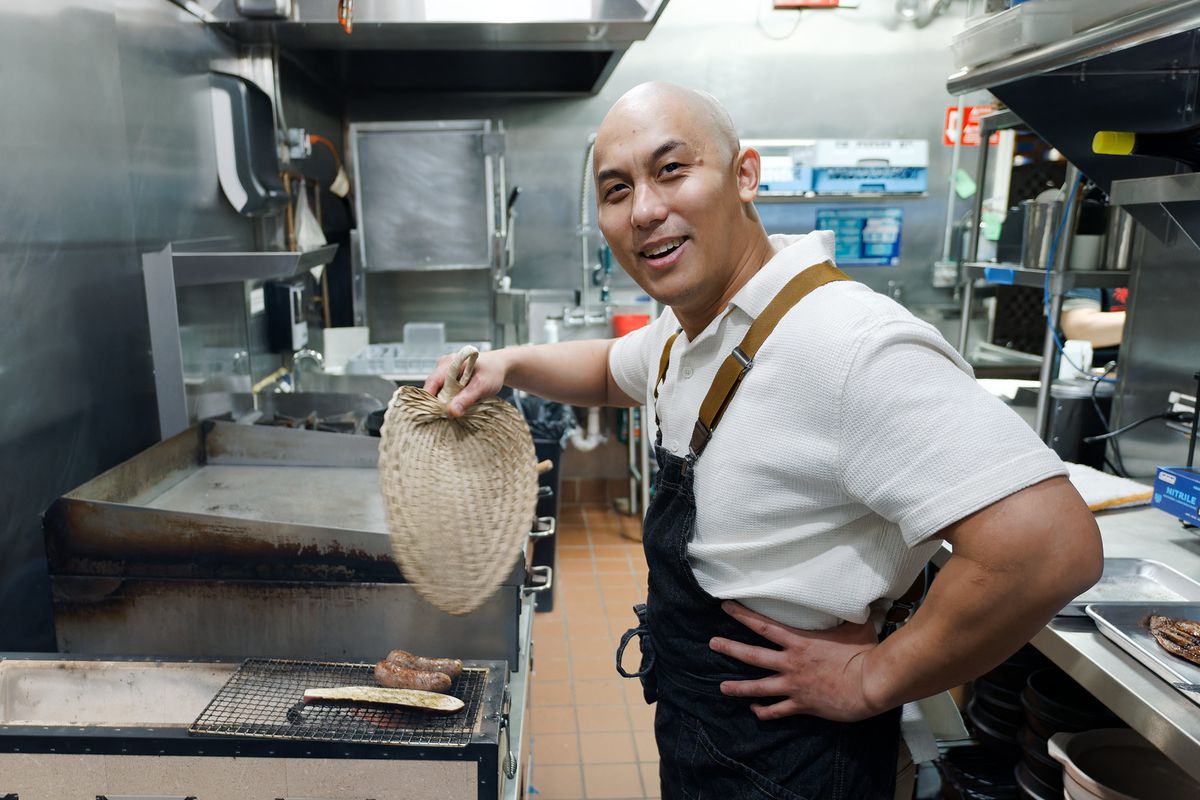 A Chef in a kitchen fanning the grill.