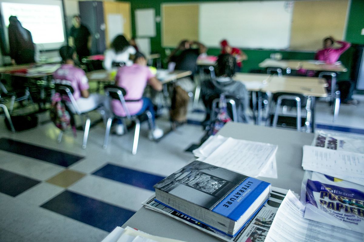 Students learning in a classroom at desks in Detroit with a literature textbook in the foreground of the photo.