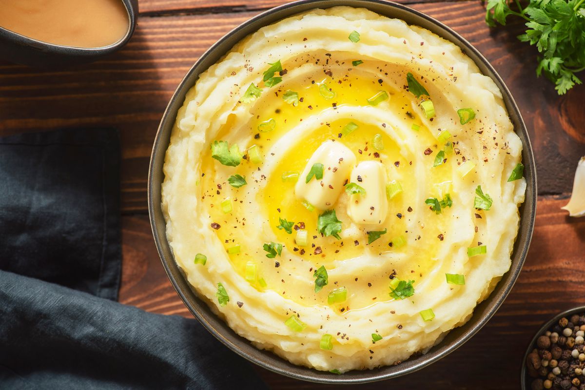 A bowl of mashed potatoes with melting butter and chives.