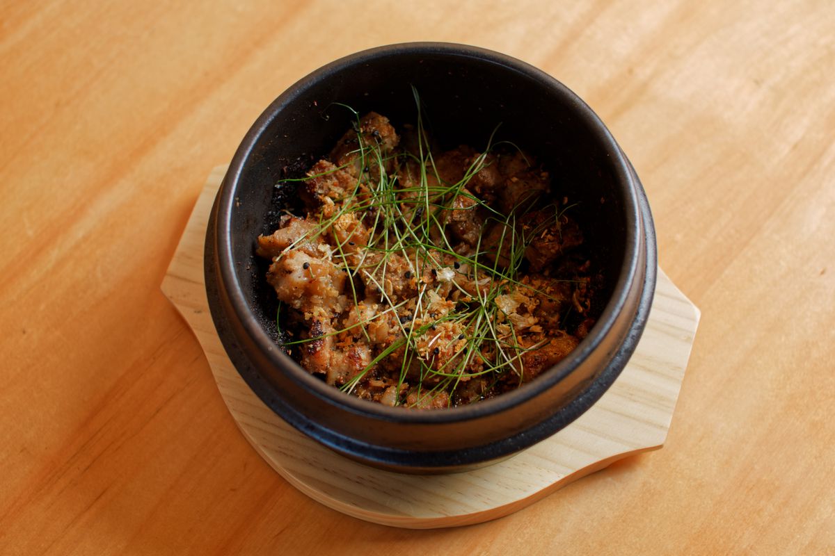 A deep bowl holds a dish of pork belly.