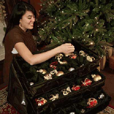 Person placing Christmas ornaments neatly in an ornament chest.