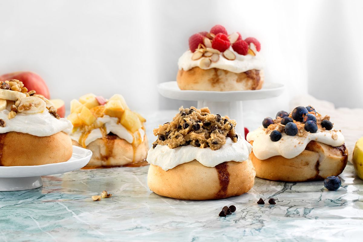A variety of Cinnaholic’s frosted cinnamon buns topped with different treats.