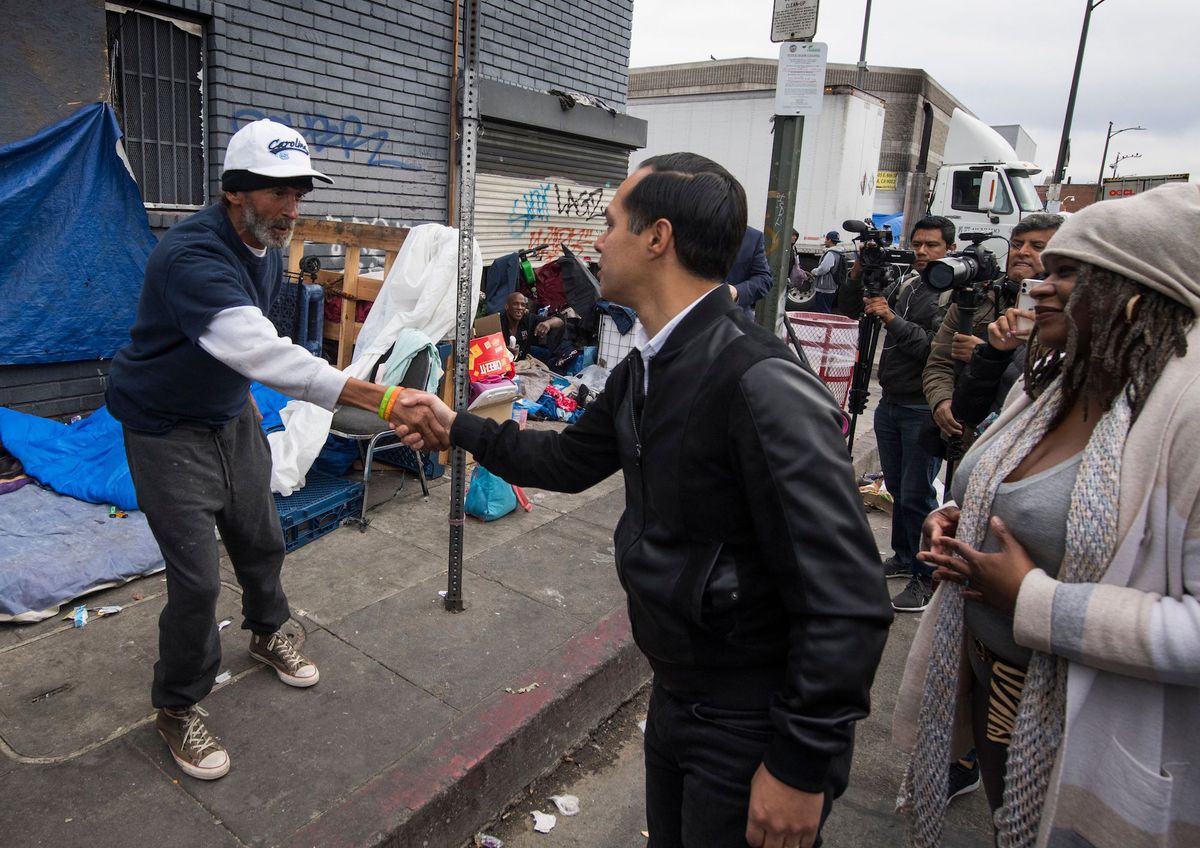 Julian Castro shakes hands with a homeless man living in a tent on a Los Angeles street.