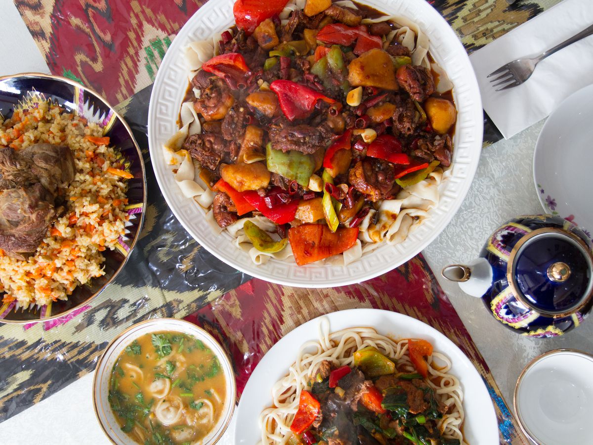 A variety of dishes, including a meat and vegetable platter, rice and noodles, and soup.