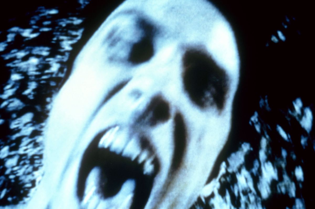A man screams into camera in close-up in grainy blue-hued video in Book of Shadows: Blair Witch 2