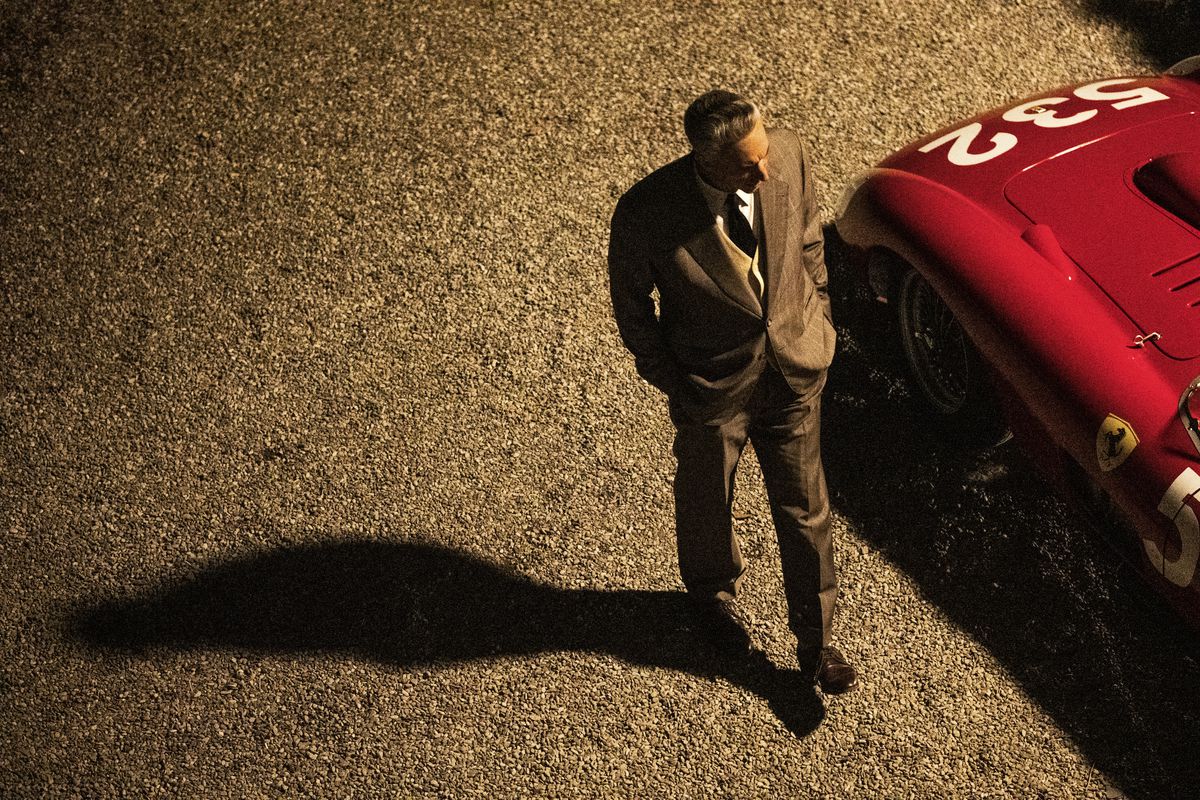 An overhead shot of Enzo Ferrari (Adam Driver) walking next to a Ferrari race car with the number 532 painted on it